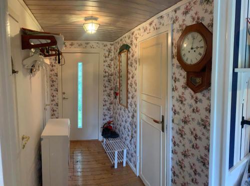 a hallway with a clock on the wall at Cozy and Private 3-Bed House with bath Roslagen in Herräng