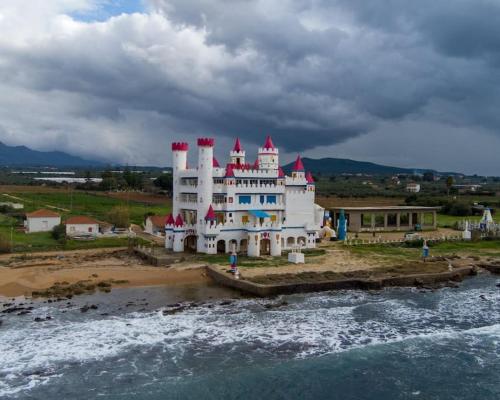 a large white building on the beach next to the water at Ginas Apartment 1 in Kyparissia