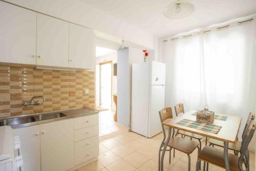 a kitchen with a table and chairs and a kitchen with white cabinets at Anthia private studio a breath away from beaches in Agios Nikitas
