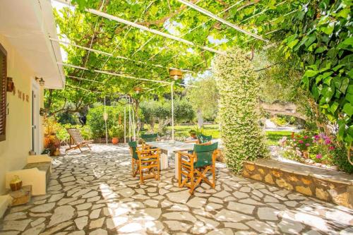 a patio with a table and chairs in a garden at Anthia private studio a breath away from beaches in Agios Nikitas