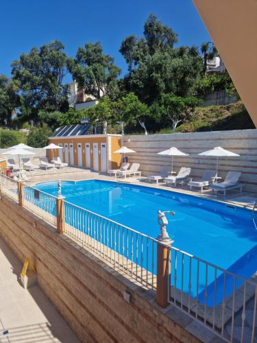 a pool at a resort with chairs and umbrellas at Valtos Ionion in Parga