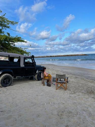 a person sitting in a chair next to a truck on the beach at Yakaduru - Yala in Yala