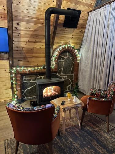 a fireplace in a room with two chairs and a table at DELLA SUİT BUNGALOW in Çamlıhemşin