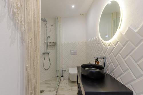 Un baño con un lavabo negro y un espejo. en Petite Maison Lili by Caleta Homes, en Málaga