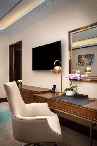 a room with a desk with a television and a chair at Blossom Hotel Houston, Curio Collection by Hilton in Houston
