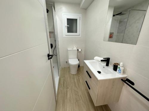 a white bathroom with a toilet and a sink at Apartamento Galiria, Pals in Pals