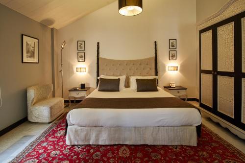 a bedroom with a large bed and a chair at Cherry Blossom Boutique Hotel in Bḩamdūn