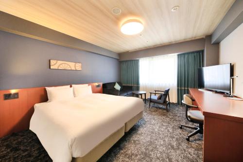 a hotel room with a large bed and a desk at Richmond Hotel Yokohama-Bashamichi in Yokohama