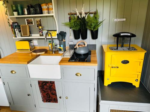 cocina con fregadero y estufa amarilla en Miners Hut en St Austell