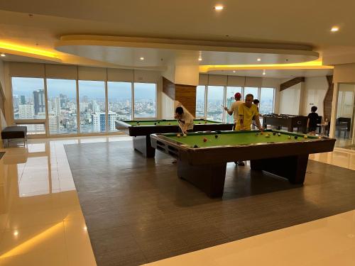 two men playing pool in a room with a pool table at JC Condo, SMDC Green Malate Taft Manila in Manila