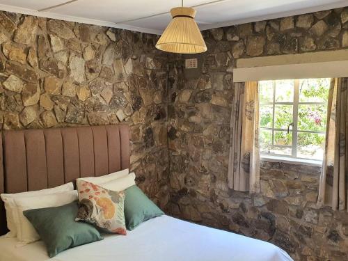 1 dormitorio con pared de piedra y 1 cama con almohadas en 10 guest stay in the mountains of Nyanga! en Juliasdale