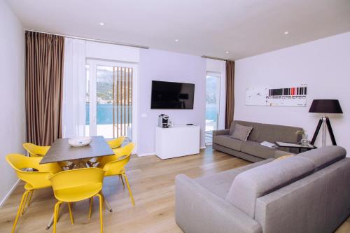 a living room with a couch and a table and yellow chairs at Ah Porticcioli Boutique Apartments in San Felice del Benaco