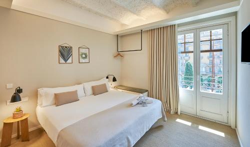 Un dormitorio con una gran cama blanca y una ventana en The Moods Catedral Hostal Boutique, en Barcelona