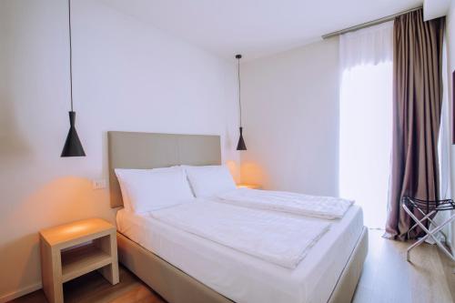 a bedroom with a white bed and a window at Ah Porticcioli Boutique Apartments in San Felice del Benaco