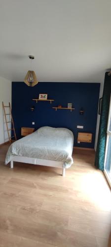 une chambre avec un lit et un mur bleu dans l'établissement Maison récente avec jardin., à Plourhan