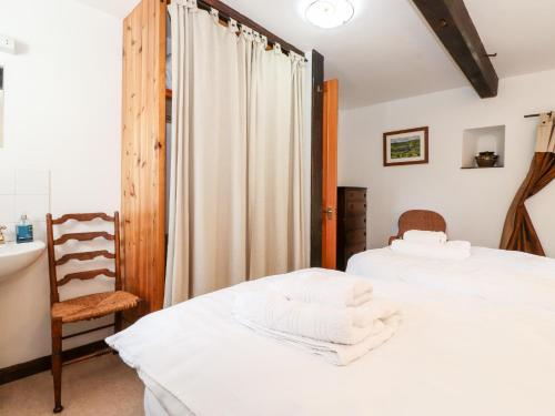 a bedroom with two beds and a chair at Cranesbill Barn in Kirkby Stephen