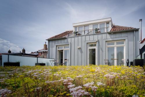 a white house with windows and a field of flowers at Hotel De Zilte Zeeuw in Kortgene