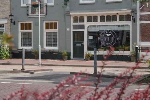 a coffee shop with a sign in front of a building at Hotel De Zilte Zeeuw in Kortgene