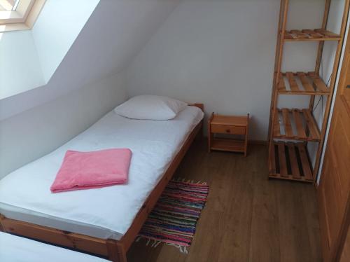 a small bedroom with a bed with a pink pillow at Domki Afrodyta in Jarosławiec