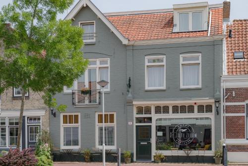 a gray house with a sign in front of it at Hotel De Zilte Zeeuw in Kortgene