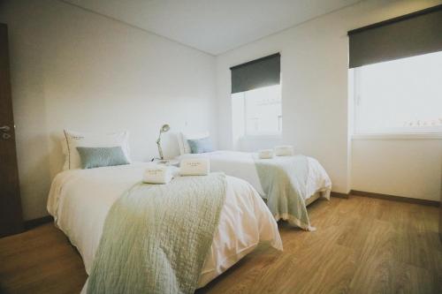 a bedroom with two beds with white sheets and a window at CASA DA RIBEIRA in Viana do Castelo