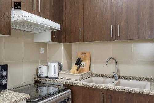 a kitchen with wooden cabinets and a counter top at Mira Holiday Homes - Beautiful Studio in Living Legends in Dubai