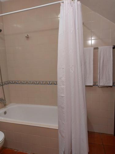 baño con bañera y cortina de ducha blanca en Janelas de Monsaraz en Telheiro