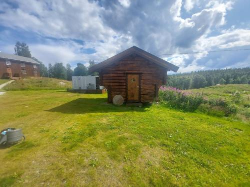 uma pequena cabana de madeira num campo de relva em small camping cabbin with bathroom near by em Hattfjelldal
