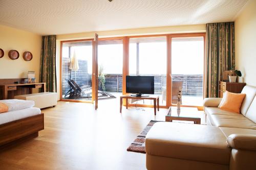 a living room with a couch and a tv at Genusshotel Riegersburg in Riegersburg