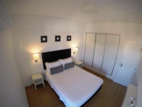 Monte Gordo Prestige Apartments في مونت غوردو: غرفة نوم بسرير ابيض مع وسادتين
