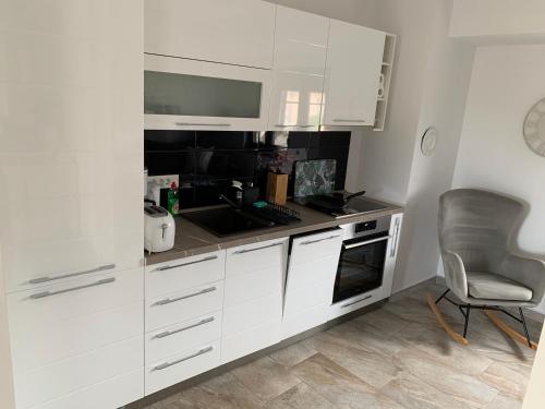 a white kitchen with a sink and a chair at House between beaches in Vir