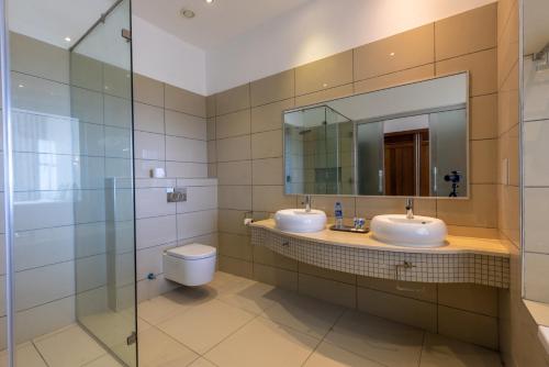 a bathroom with two sinks and a mirror and a toilet at Sun N Sand Beach Resort in Mombasa