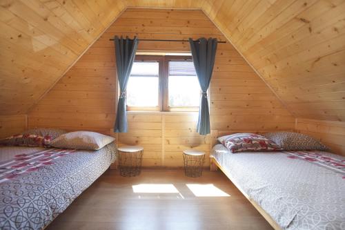 2 camas en una cabaña de madera con ventana en LAZUROWY ZAKĄTEK, en Niechorze
