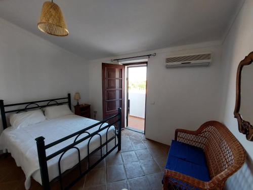 1 dormitorio con 1 cama, 1 silla y 1 puerta en Janelas de Monsaraz en Telheiro