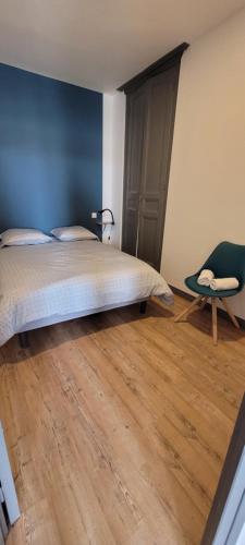 a bedroom with a bed and a chair on a wooden floor at Gîte la rose des vents N 1 in Saint-Vaast-la-Hougue