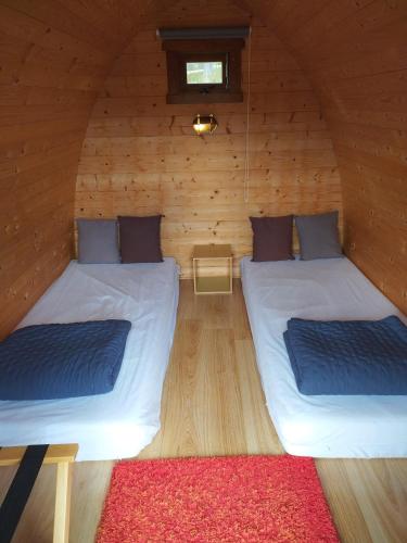 - 2 lits dans une chambre en bois avec un tapis rouge dans l'établissement Les Chalets du Haut-Forez, à Usson-en-Forez