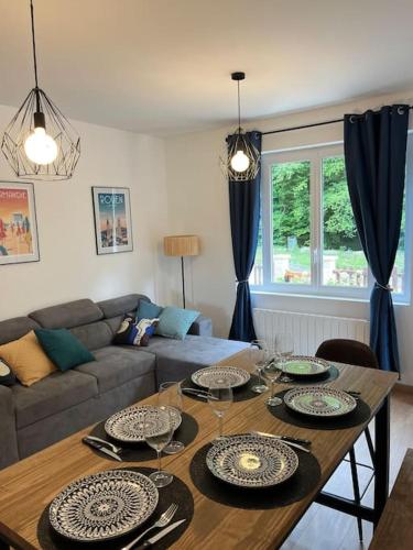 - un salon doté d'une table avec des assiettes et des verres à vin dans l'établissement Chez Mélanie, près de l’abbaye, à Jumièges