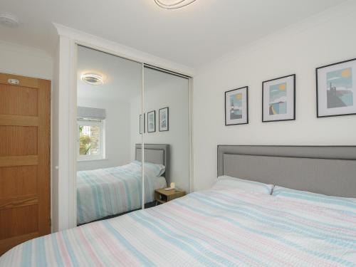1 dormitorio con cama y espejo grande en Wheal Charlotte Cottage, en Penzance