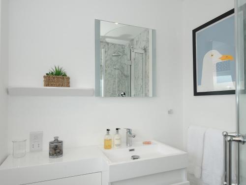 a white bathroom with a sink and a mirror at Wheal Charlotte Cottage in Penzance