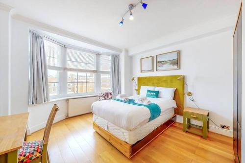 een slaapkamer met een bed, een bureau en een raam bij Vibrant and sunny 2 BR apartment in Hyde Park in Londen