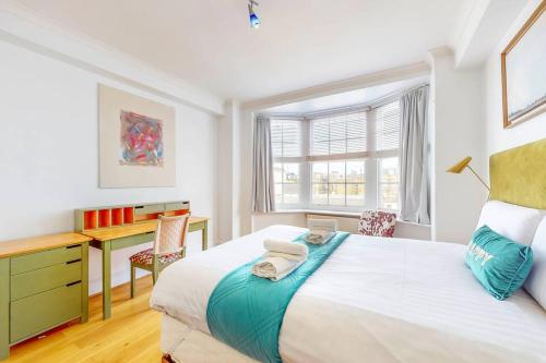 een slaapkamer met een bed, een bureau en een raam bij Vibrant and sunny 2 BR apartment in Hyde Park in Londen
