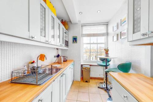 een keuken met witte kasten en een wastafel bij Vibrant and sunny 2 BR apartment in Hyde Park in Londen