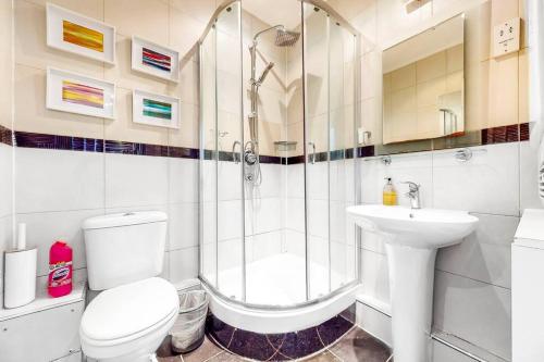 een badkamer met een douche, een toilet en een wastafel bij Vibrant and sunny 2 BR apartment in Hyde Park in Londen