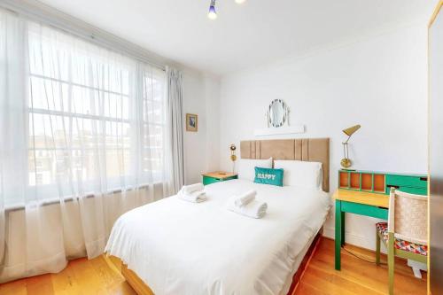 een slaapkamer met een groot wit bed en een raam bij Vibrant and sunny 2 BR apartment in Hyde Park in Londen