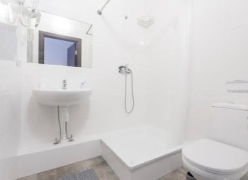 La salle de bains blanche est pourvue de toilettes et d'un lavabo. dans l'établissement Smart Hotel Rooms near metro 24/7, à Kiev