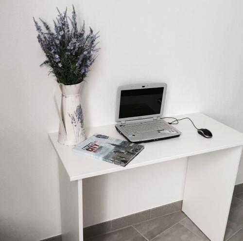 einen weißen Schreibtisch mit einem Laptop und einer Blumenvase in der Unterkunft Smart Hotel Rooms near metro 24/7 in Kiew