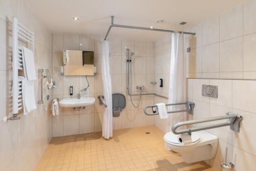 a bathroom with a shower and a toilet and a sink at IntercityHotel Berlin Airport Area North in Schönefeld