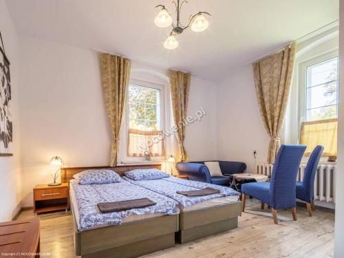 1 dormitorio con 1 cama y 2 sillas azules en Willa Dunajec, en Kudowa-Zdrój