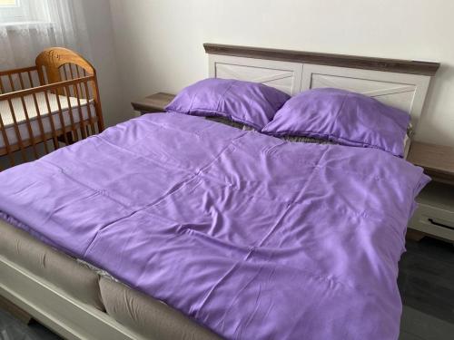 a bed with a purple comforter and pillows at Bezbariérový apartmán Lodenica - v tesnej blízkosti Adelli centra in Piešťany