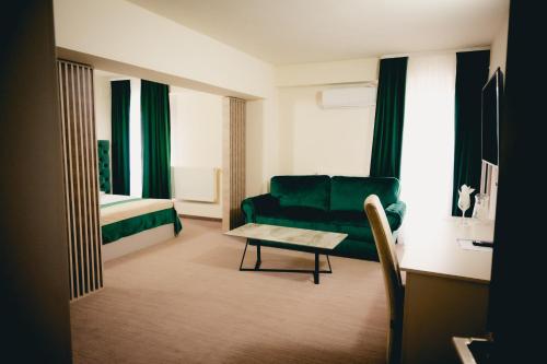 a living room with a green couch and a table at Hotel Valahia in Târgovişte